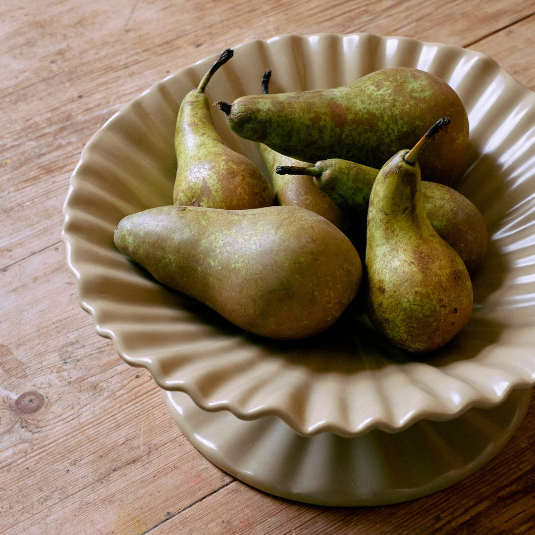 Pears on a decorative ceramic plate on a wooden surface
