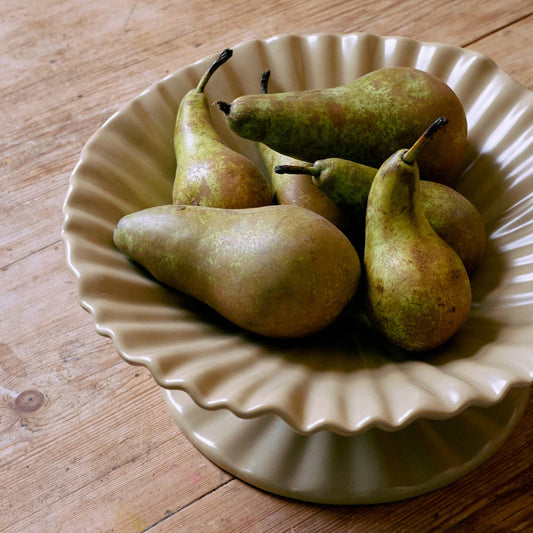 Pears on a decorative ceramic plate on a wooden surface