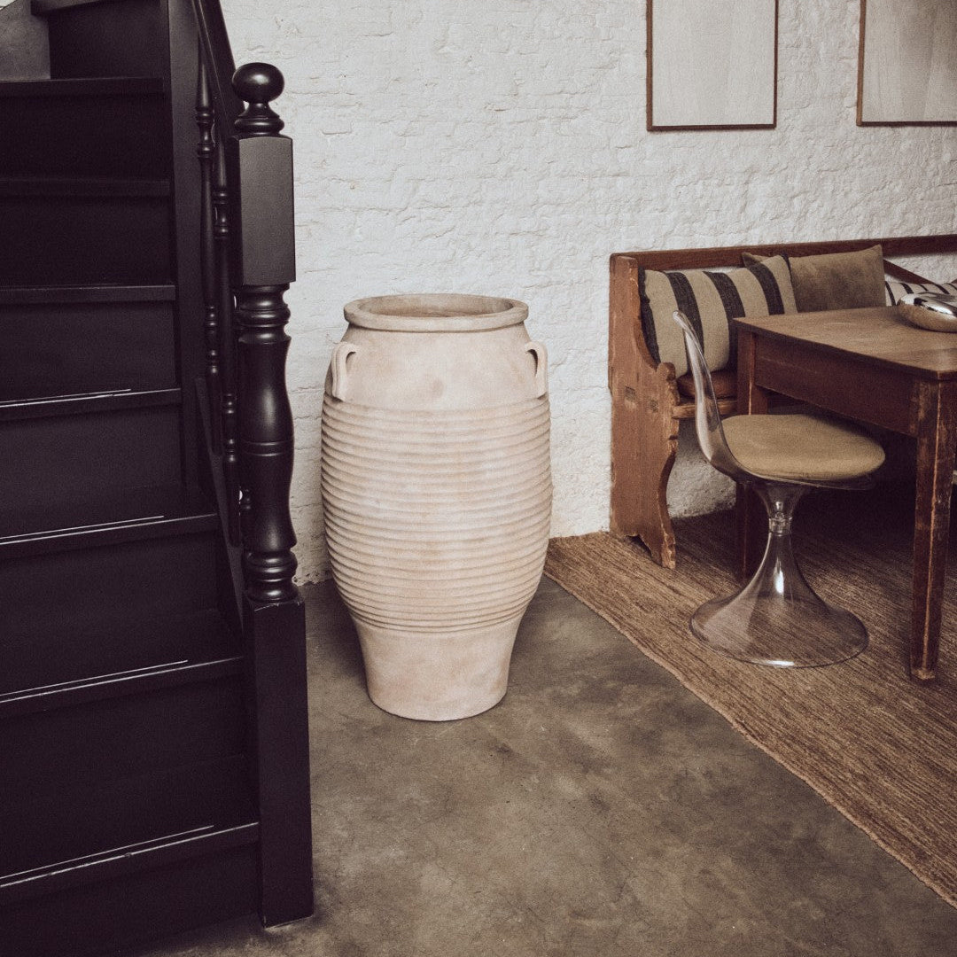 Narrow staircase leading to an upper level with a textured white wall and wooden furniture.
