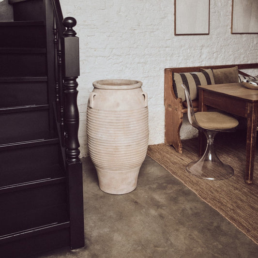 Narrow staircase leading to an upper level with a textured white wall and wooden furniture.