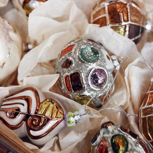Decorative Christmas ornaments with gemstone-like embellishments in a box.