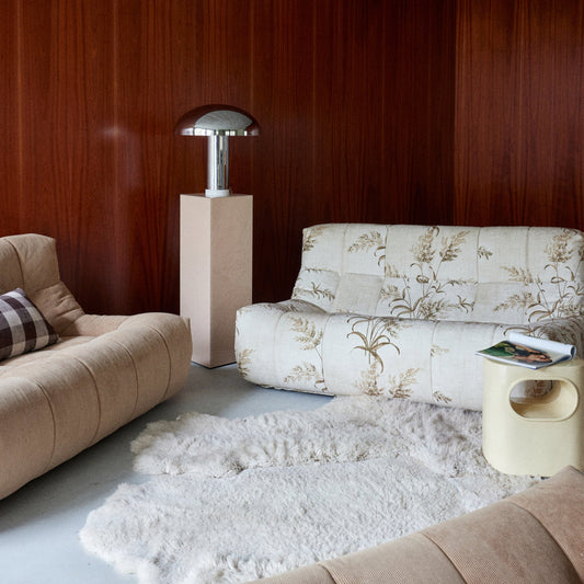 Modern living room with beige sofas, a floral-patterned sofa, and a lamp.
