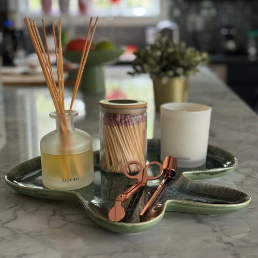 Decorative items including a diffuser, candles, and a tray on a marble surface.