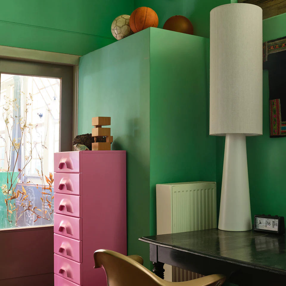 Room interior with pink cabinet, green wall, and a lamp.