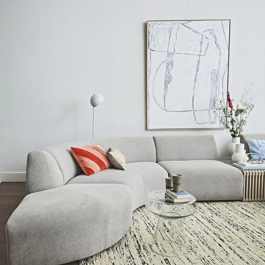 Modern living room with a gray sectional sofa, abstract art, and decorative items.