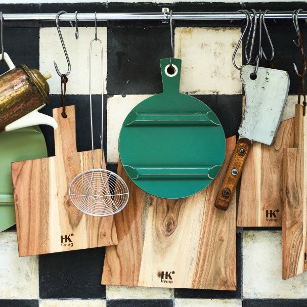 Set of wooden cutting boards and kitchen tools hanging on a tiled wall.