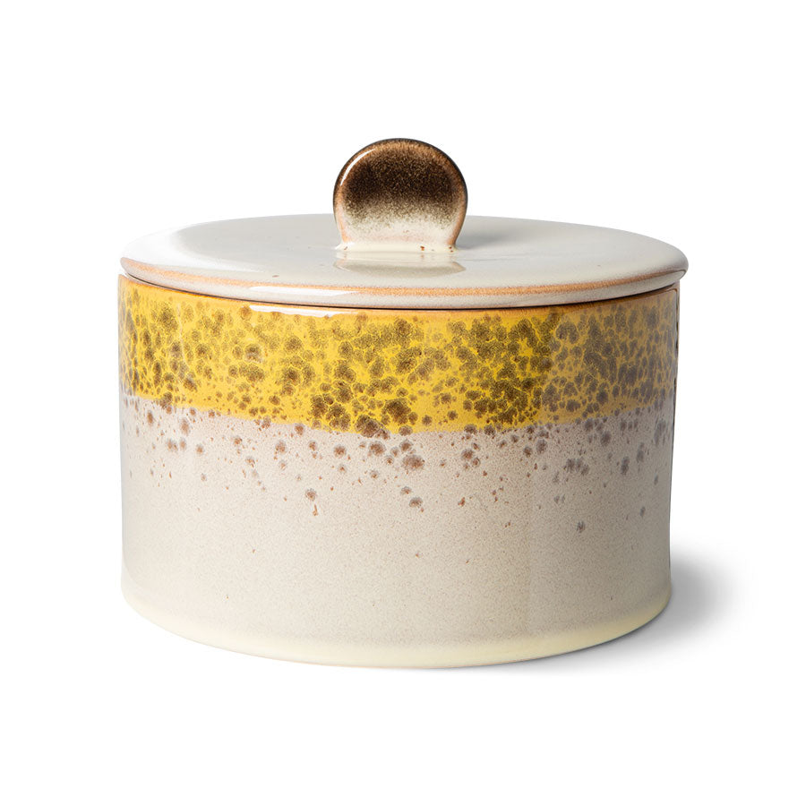 Ceramic jar with a yellow accent and gold lid on a white background
