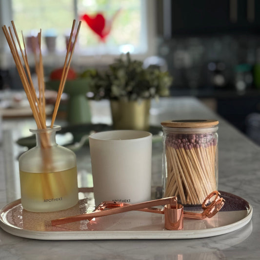 Decorative items including a diffuser, candle, and matches on a marble surface.