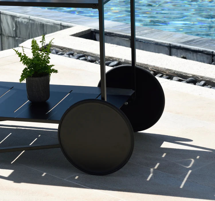 Black outdoor furniture set with a table and chairs by a poolside.